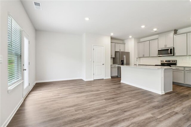 kitchen with a healthy amount of sunlight, light countertops, stainless steel appliances, and tasteful backsplash