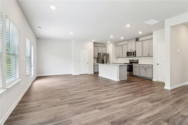 kitchen with gray cabinetry, stainless steel appliances, wood finished floors, and open floor plan