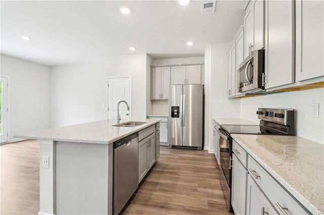 kitchen with stainless steel appliances, wood finished floors, visible vents, and a sink