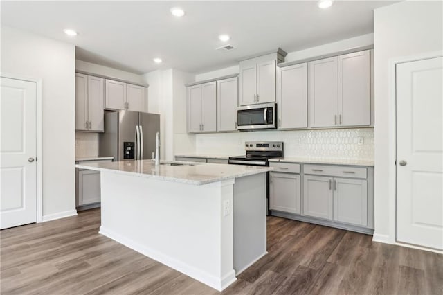 kitchen with a sink, a kitchen island with sink, gray cabinets, and appliances with stainless steel finishes