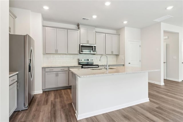 kitchen featuring a sink, stainless steel appliances, visible vents, dark wood-type flooring, and tasteful backsplash