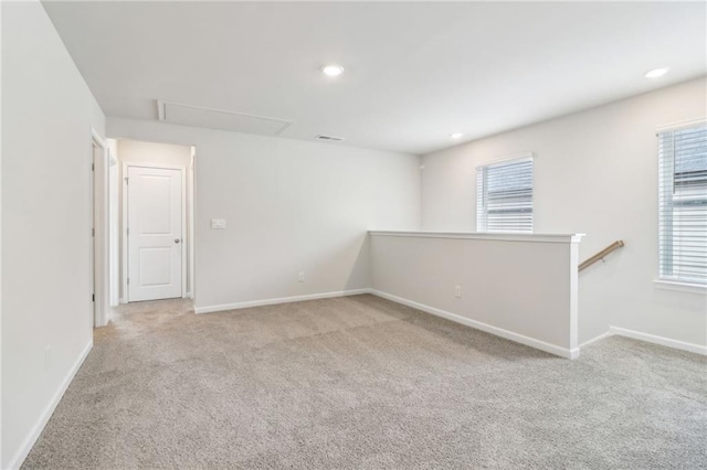 unfurnished room with a healthy amount of sunlight, attic access, baseboards, and carpet