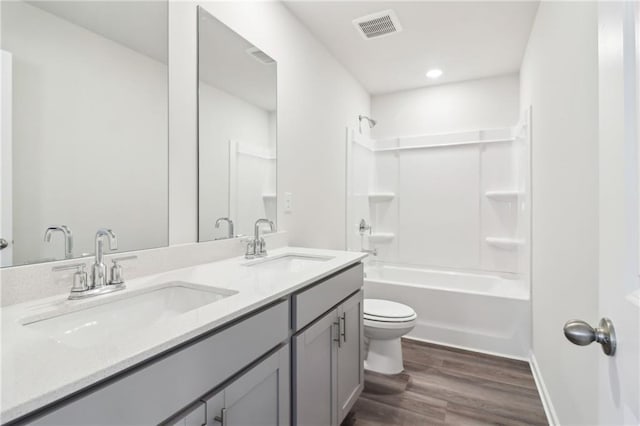 full bath featuring toilet, visible vents, wood finished floors, and a sink
