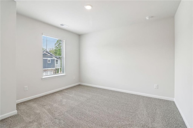 carpeted spare room featuring baseboards and visible vents