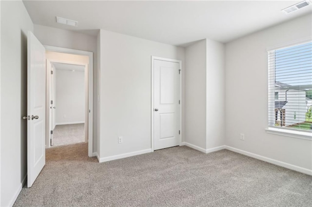 unfurnished bedroom featuring multiple windows, visible vents, and carpet