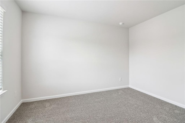 spare room with baseboards and carpet floors