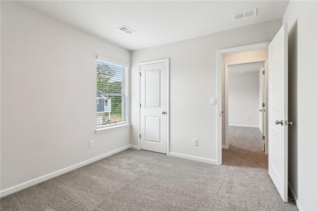 unfurnished bedroom featuring baseboards, visible vents, and carpet
