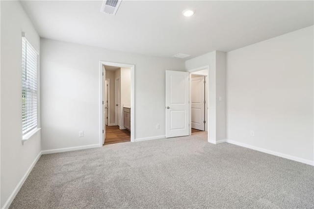 unfurnished bedroom featuring carpet flooring, baseboards, visible vents, and multiple windows