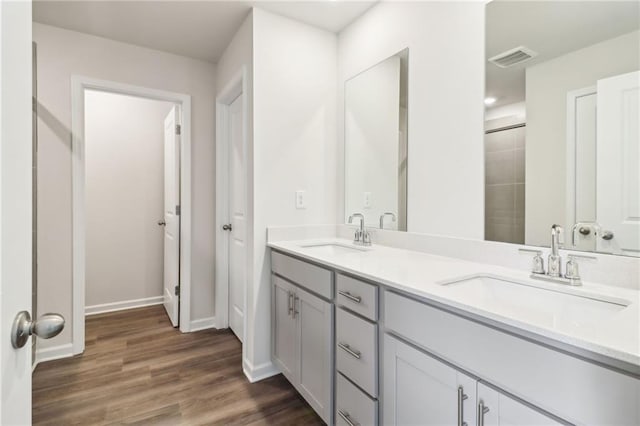 bathroom featuring baseboards, visible vents, a sink, and wood finished floors