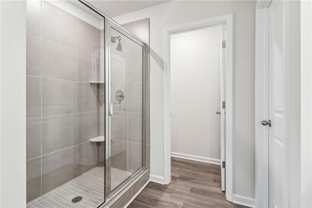 bathroom with baseboards, wood finished floors, and a stall shower