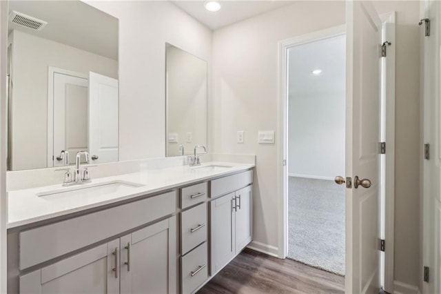 bathroom featuring double vanity, visible vents, wood finished floors, and a sink