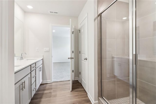 full bathroom featuring a shower stall, visible vents, a sink, and wood finished floors