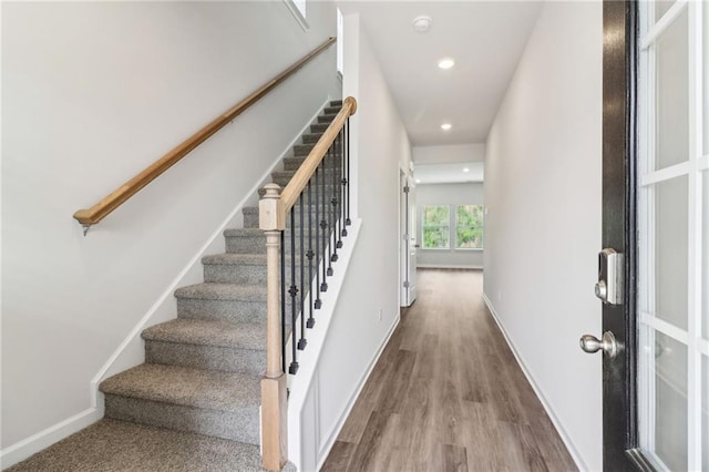 staircase featuring wood finished floors, baseboards, and recessed lighting