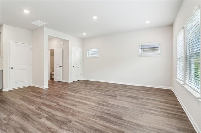 unfurnished room with visible vents, wood finished floors, baseboards, and recessed lighting