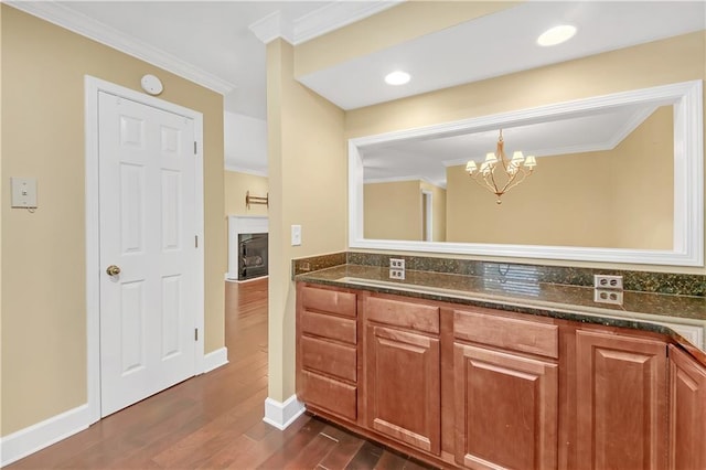 bathroom featuring vanity, hardwood / wood-style floors, crown molding, and a chandelier