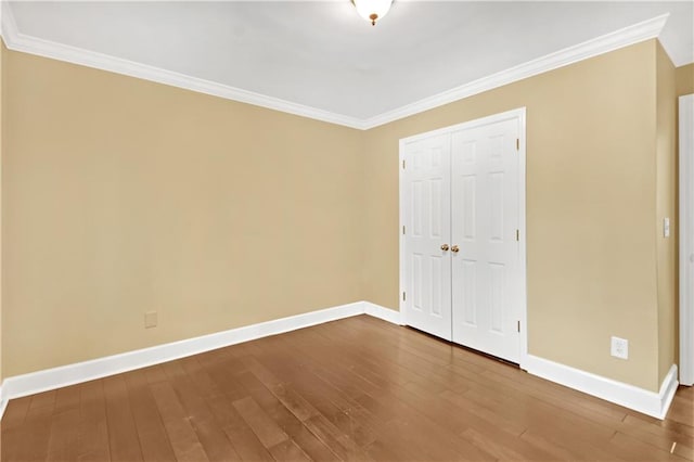 unfurnished bedroom with crown molding, wood-type flooring, and a closet