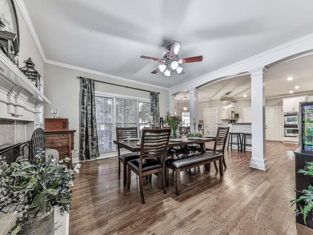 dining room featuring ornate columns, hardwood / wood-style flooring, ceiling fan, and ornamental molding