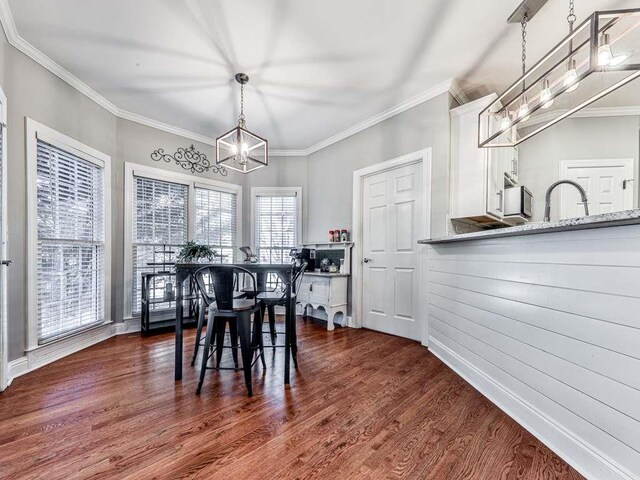 dining space featuring dark hardwood / wood-style floors, ornamental molding, and a notable chandelier