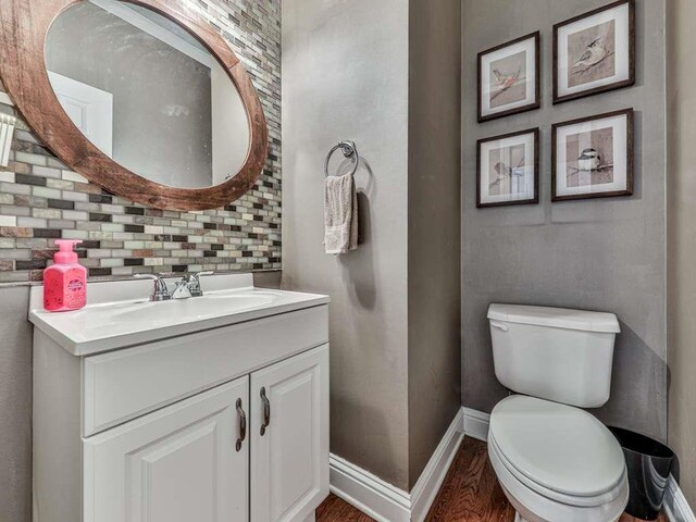 bathroom with wood-type flooring, vanity, tasteful backsplash, and toilet