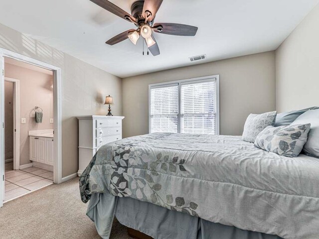 carpeted bedroom with ensuite bath and ceiling fan