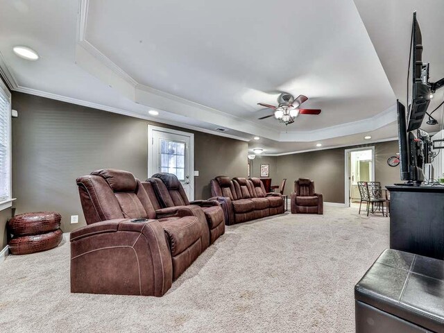 carpeted cinema room with a raised ceiling, ceiling fan, and ornamental molding