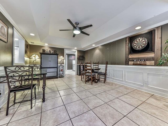 tiled dining area featuring ceiling fan and a tray ceiling