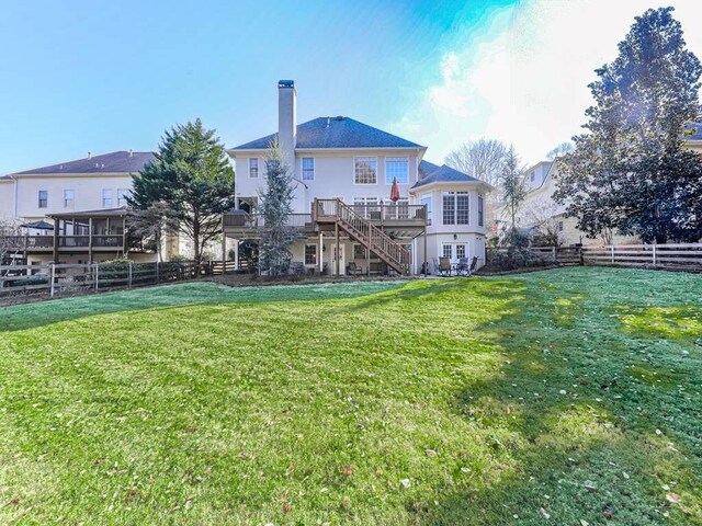 rear view of property featuring a deck and a lawn