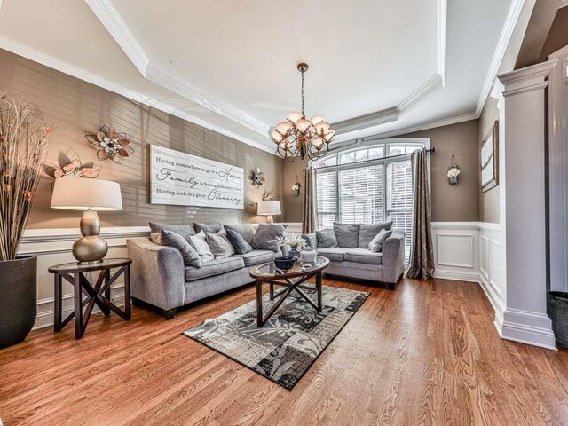 living room featuring a raised ceiling, hardwood / wood-style flooring, crown molding, and a notable chandelier