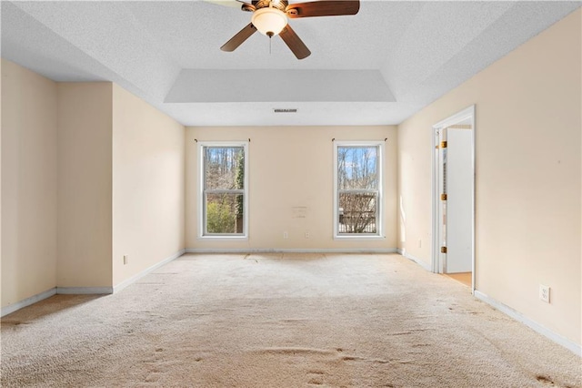 spare room featuring a textured ceiling, ceiling fan, a tray ceiling, and light colored carpet