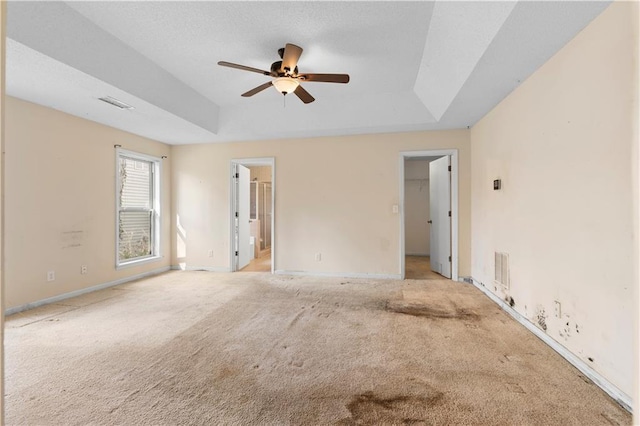 spare room with ceiling fan, light colored carpet, and a raised ceiling