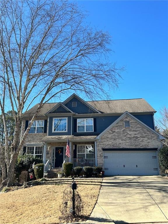 view of front of house with driveway, a porch, a shingled roof, a garage, and brick siding