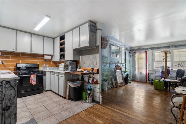 1550 Bells Ferry Rd, Marietta, GA 30066 - kitchen with black gas stove, backsplash, light wood-type flooring, and light countertops