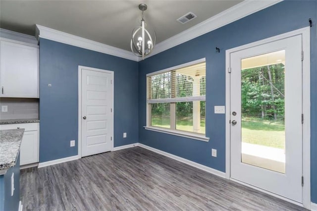 unfurnished dining area featuring a chandelier, dark wood-type flooring, crown molding, and baseboards