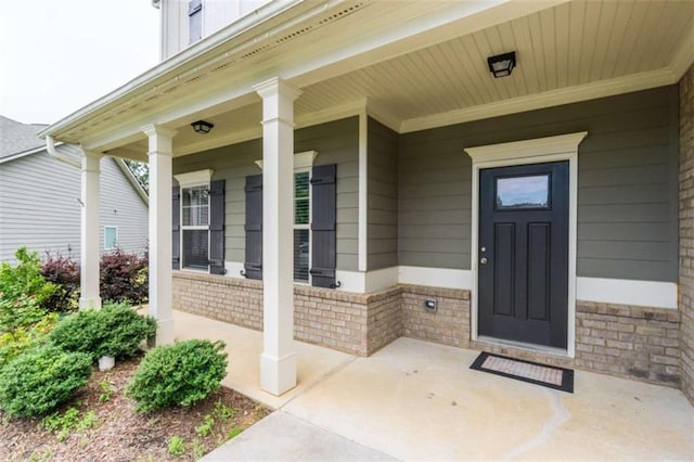 entrance to property featuring covered porch and brick siding