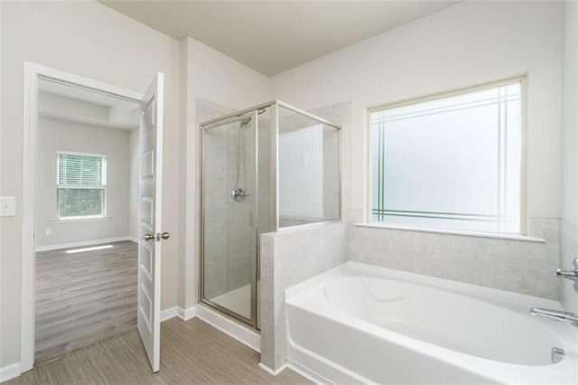 full bathroom with a stall shower, a bath, and baseboards