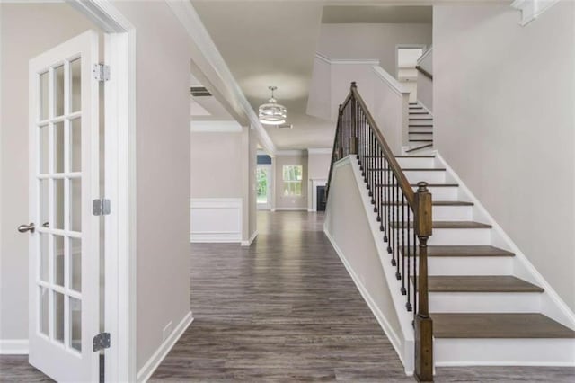 stairway featuring wood finished floors, ornamental molding, a chandelier, and baseboards