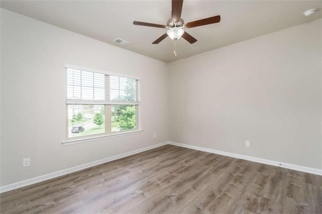 spare room featuring wood finished floors, a ceiling fan, baseboards, and a smoke detector