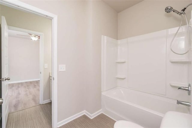 bathroom featuring toilet, baseboards, shower / tub combination, and wood finished floors