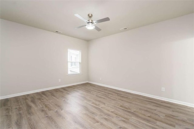 spare room with wood finished floors, ceiling fan, and baseboards