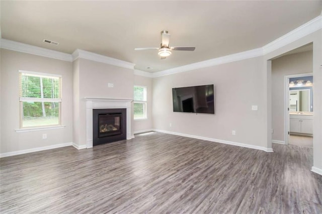 unfurnished living room featuring wood finished floors, ceiling fan, ornamental molding, plenty of natural light, and a glass covered fireplace