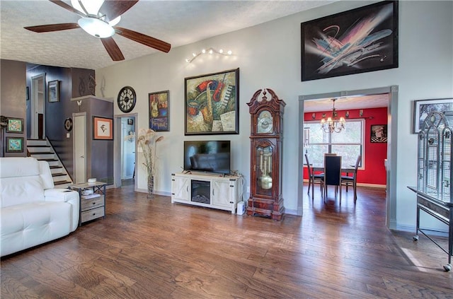 living room with a textured ceiling, dark hardwood / wood-style floors, and ceiling fan with notable chandelier