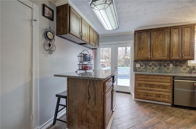 kitchen with backsplash, dishwasher, dark wood-type flooring, dark stone countertops, and a breakfast bar area