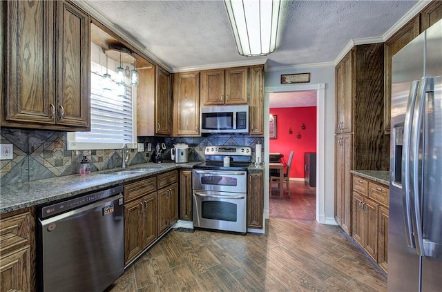 kitchen with sink, dark stone counters, stainless steel appliances, dark hardwood / wood-style flooring, and decorative backsplash