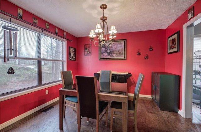 dining room with a chandelier, dark hardwood / wood-style floors, and a textured ceiling