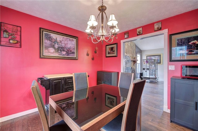 dining room with an inviting chandelier, a textured ceiling, and dark hardwood / wood-style floors