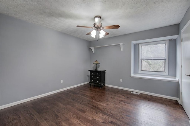 empty room featuring dark hardwood / wood-style flooring, ceiling fan, and a textured ceiling