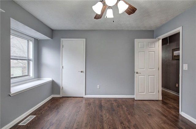 unfurnished bedroom featuring a textured ceiling, dark hardwood / wood-style floors, and ceiling fan