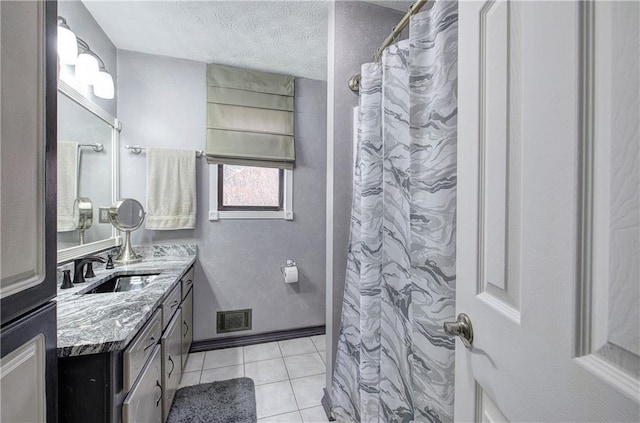 bathroom with tile patterned floors, vanity, a textured ceiling, and walk in shower