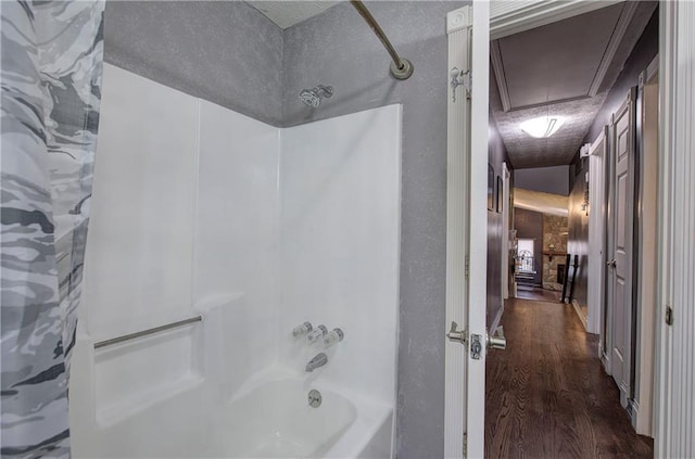 bathroom featuring hardwood / wood-style flooring, bathing tub / shower combination, and a textured ceiling