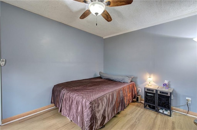 bedroom featuring ceiling fan, light hardwood / wood-style flooring, crown molding, and a textured ceiling